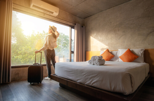 Single woman stares out hotel room alone thinking about her divorce