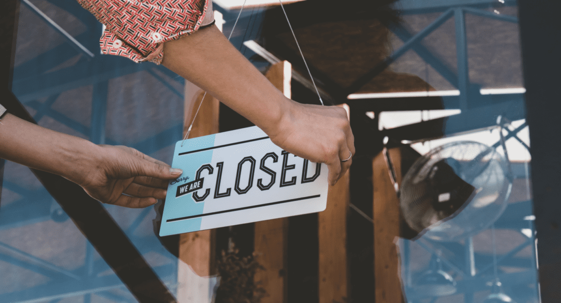 Caucasian female turning sign from open to closed on the entrance door of his small cafe Out of business