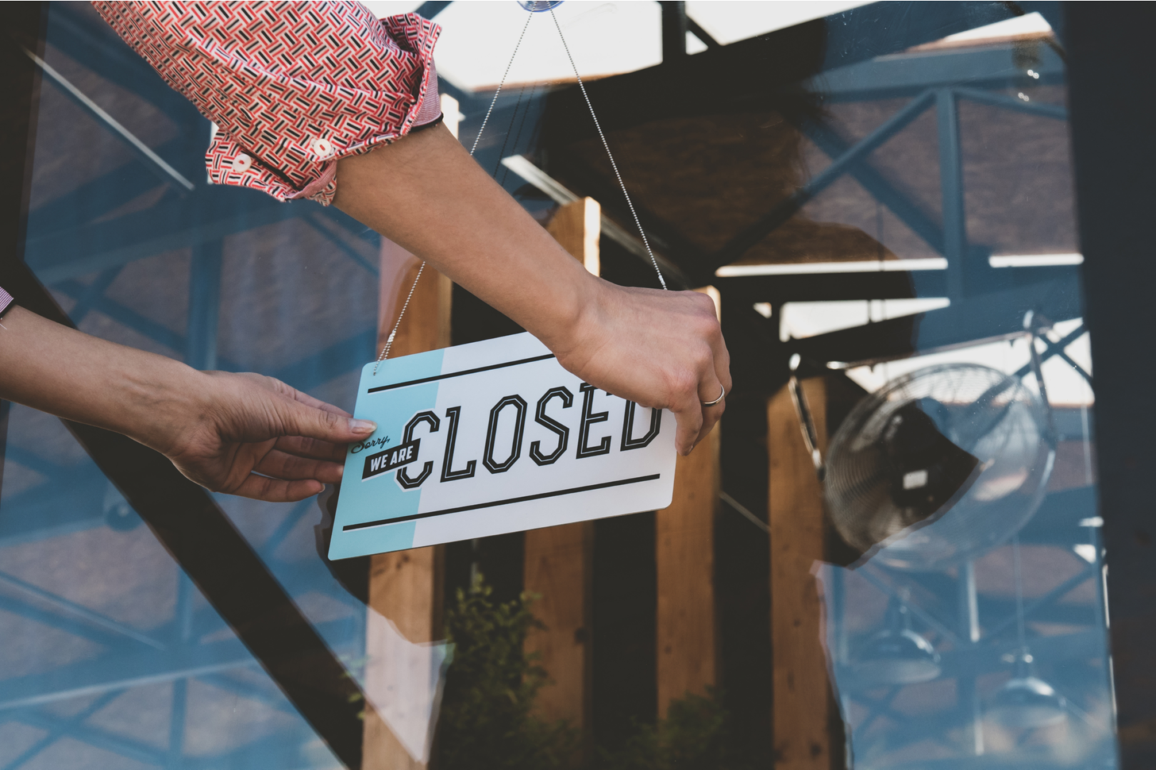 Caucasian female turning sign from open to closed on the entrance door of his small cafe Out of business