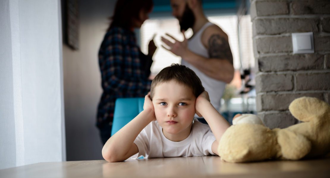 Sad, desperate little boy during parents quarrel. Clog the ears.