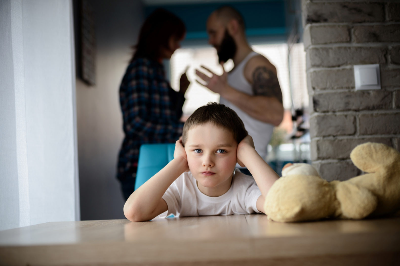 Sad, desperate little boy during parents quarrel. Clog the ears.